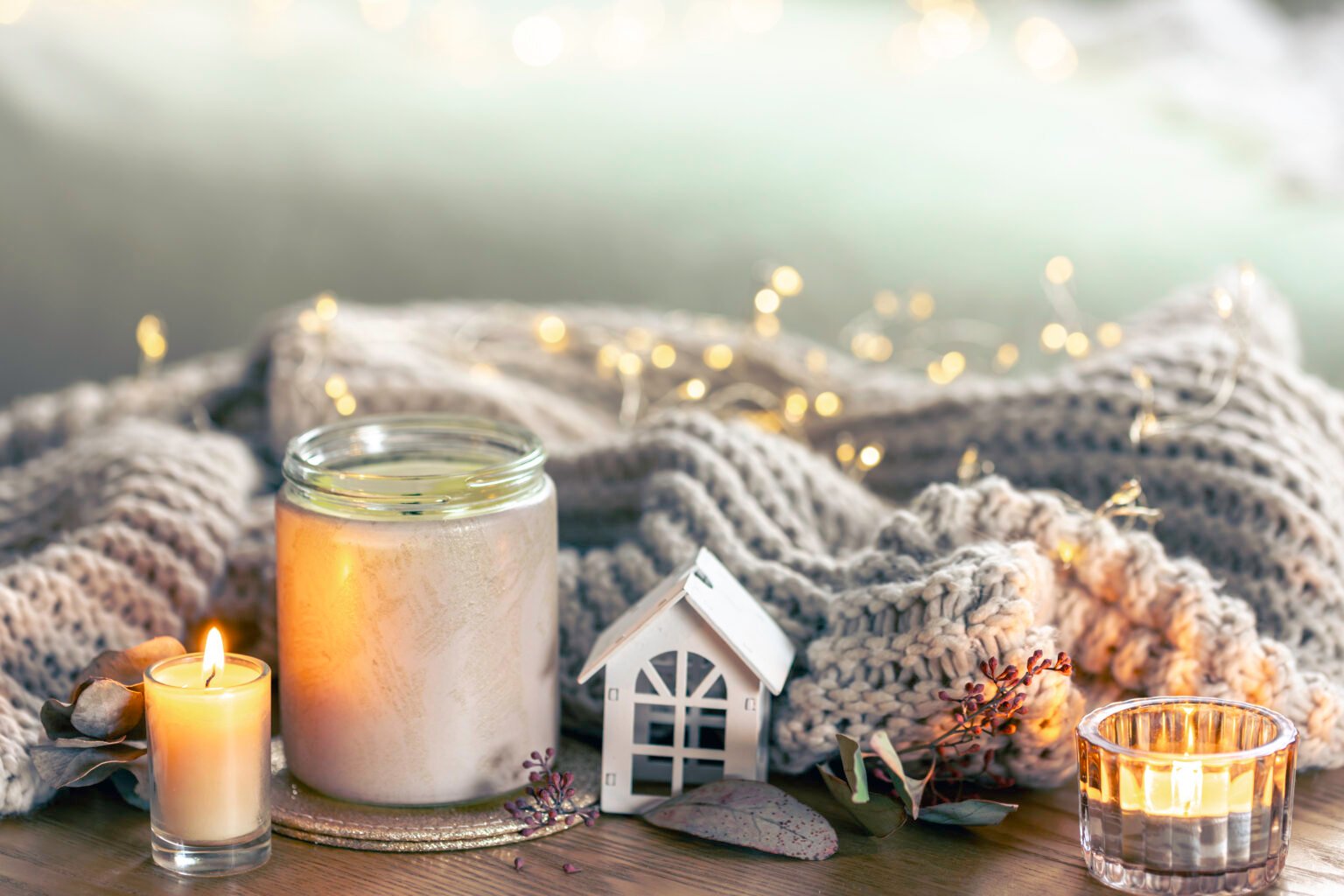 cozy composition with candles and a knitted element on a blurred background.
